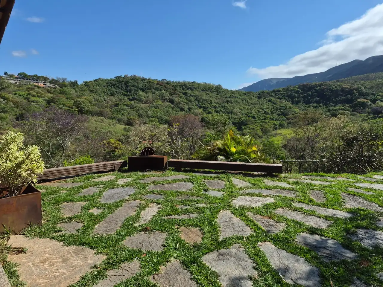 Varanda de pedra com banco de madeira e vista para a serra