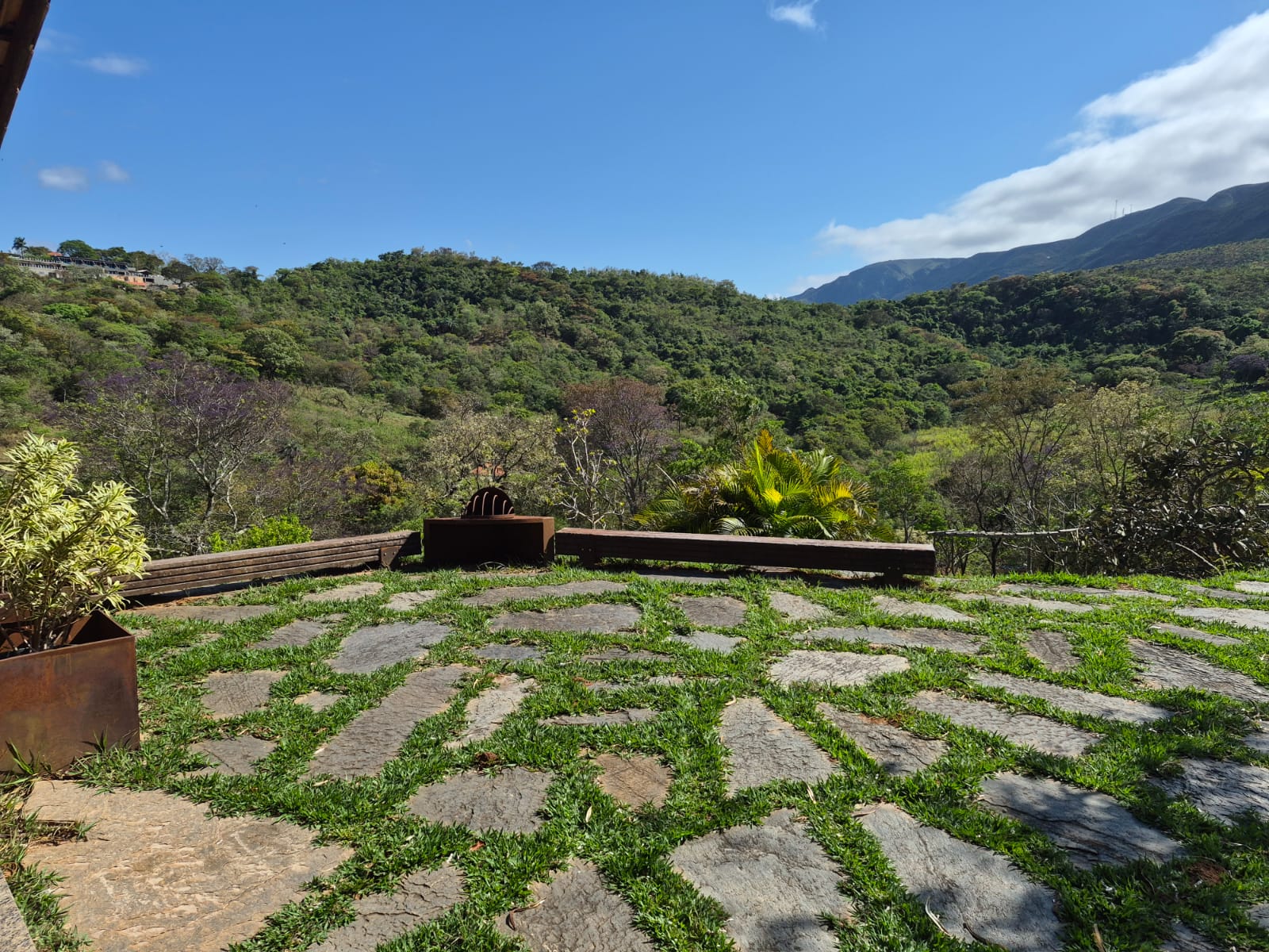 Varanda de pedra com banco de madeira e vista para a serra